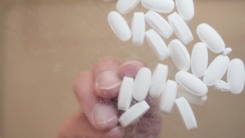 A woman pharmacist grabs prescription pills in slow motion. The pain killers represent pharmaceutical substance abuse, recreational drug use of opiates and the repeal of the affordable care act.