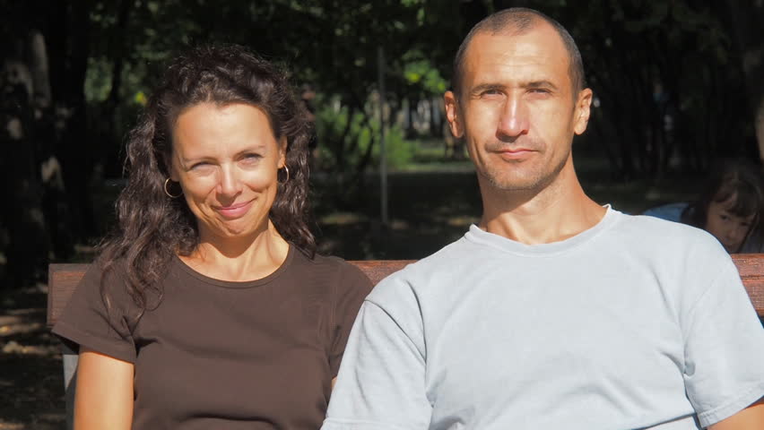 Happy family in the park. The little girl closes her eyes to her parents.