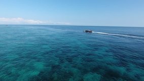 This video shows a local boat sailing over coral reefs, immersing the beautiful horizons of the endless ocean. Filmed from a chasing drone.