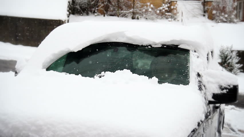 A car's windshield wipers struggle to remove the snow from the windshield during
