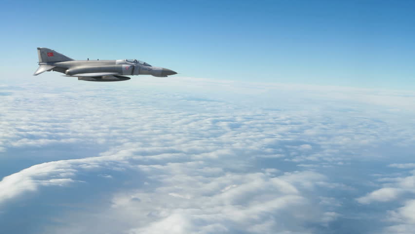 A Turkish F-4E fighter jet flying above the clouds. 