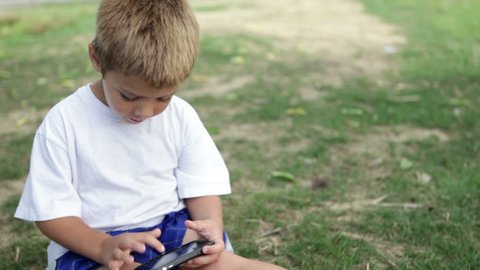 Child busy playing on cell phone in grass
