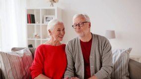 old age, blogging and people concept - happy smiling senior couple recording video message at home and showing thumbs up
