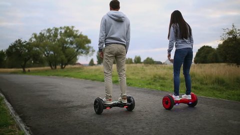 young man and woman riding on the Hoverboard in the park. content technologies. a new movement. Close Up of Dual Wheel Self Balancing Electric Skateboard Smart. on electrical scooter outdoors.