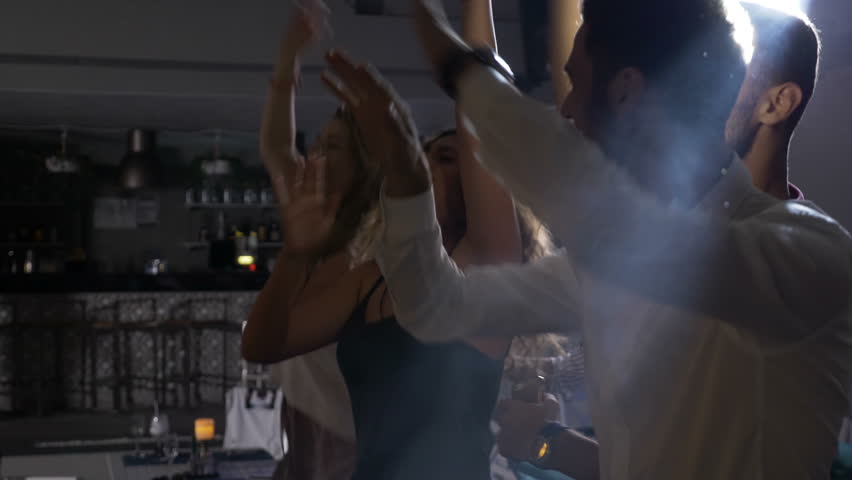 Group of teens jumping and dancing to the music at disco club party