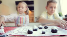 Video of two happy children having fun during preparation chocolate cookies in modern kitchen