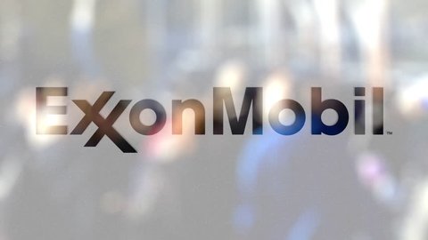 ExxonMobil logo on a glass against blurred crowd on the steet. Editorial 3D rendering