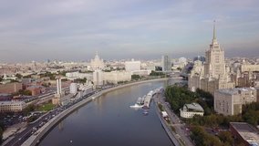 4K high quality aerial video of Moscow River in summer afternoon, landmark highrise Soviet building, distant river boats, tree-lined embankment and red brick factory buildings in Moscow, Russia