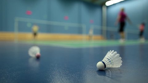 Badminton - badminton courts with players competing; shuttlecocks in the foreground (shallow DOF)