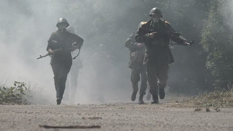 Soldiers run with gas masks through a heavy smoke