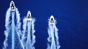 Aerial top down tracking video taken by drone of 3 speed boats cruising the Aegean deep blue sea