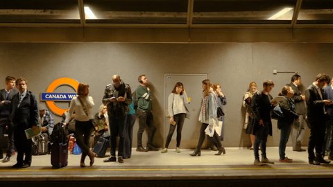 London, United Kingdom - October 20, 2017: Smooth slow motion slider camera shot of people standing and waiting for underground train in Canada Water station in London, UK