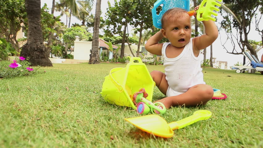 little baby sitting on the grass and playing with toys