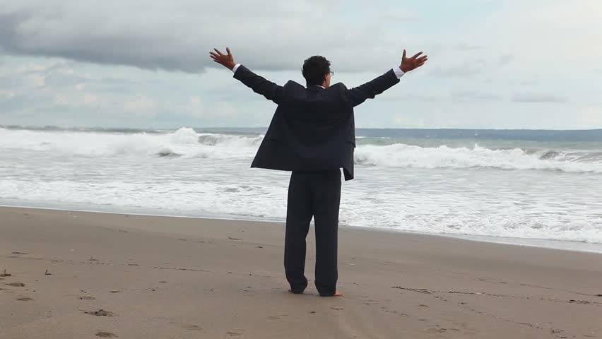 one man in official suit standing on the sea coast and looking on waves