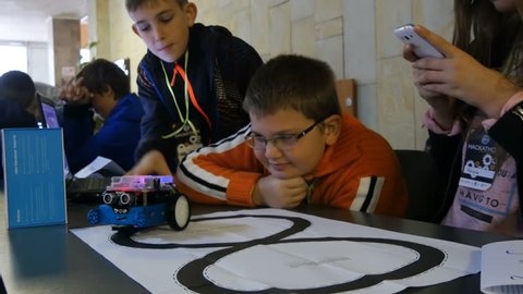 VINNITSA, UKRAINE - OCTOBER 2017: Group of smiling kids or students with tablet pc computer programming electric toy at robotics school lesson