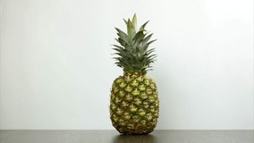 Pineapple appears in the frame, spinning and leaving the frame. One pineapple rotating on the desk on white background. Stop motion - Powered by Shutterstock - Get 15% off with code: PIKWIZARD15