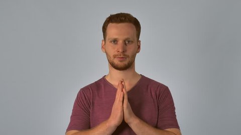 caucasian guy with red hair posing showing hand gesture east greeting or thai greeting shows respect or reverence by pressing the palms and fingers. handsome redhead men wearing in casual t-shirt