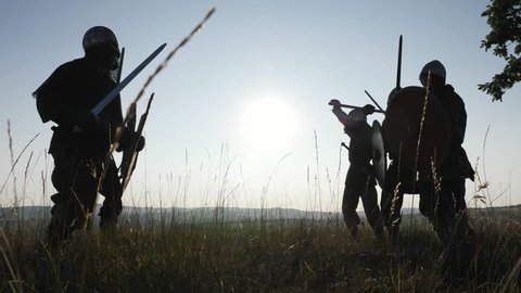 Silhouettes of Vikings warriors fighting with swords, shields. Contre-jour