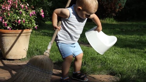 Little boy plays with a broom
