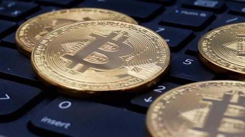 Gold Bitcoin BTC coins rotating on laptop keyboard. Digital coin btc money crypto currency on bitcoin farm in digital cyberspace. Worldwide virtual internet cryptocurrency and digital payment system