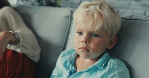 close up child is sitting on the couch looking sideways boy thought blond hair looked serious at home relaxing little portrait young Slow Motion Shot Shot on RED EPIC camera