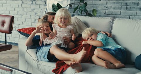 mother spending time together with children having fun on sofa sister brother rest happy playing together home family cute children boys girl hugging Slow Motion Shot Shot on RED EPIC camera