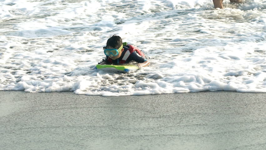 Father with son having fun with surfing board in sea, super slow motion 120fps
