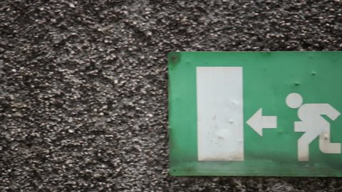 emergency exit sign, rusty signboard of person going out of the door (panning shot)