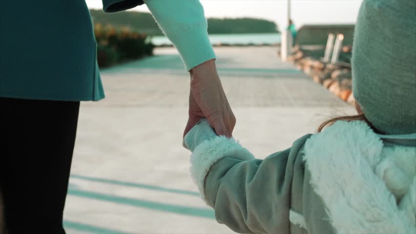 Mother hold the hand of little kid daughter