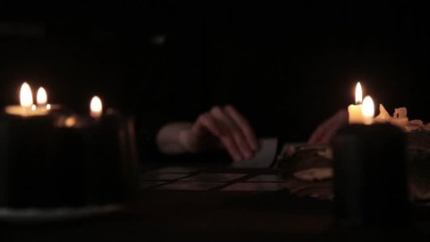 mystical beautiful woman in a black dress, divination on cards by candlelight