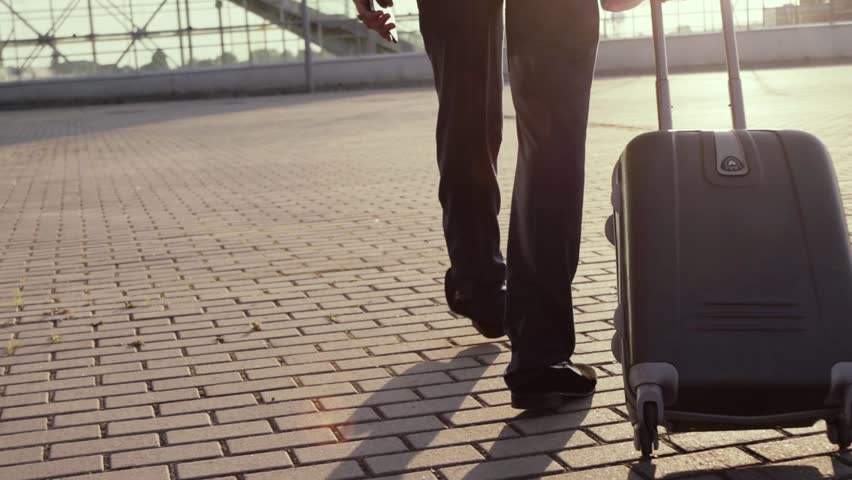 Young Man Pulling a Suitcase, Talking Via his Cellphone in a Bright Sunlight. Stylish look, elegant suit. Active Lifestyle, Cheerful Mood, Positive Emotions. Business Trip, Way Back Home. Royalty-Free Stock Footage #32030161