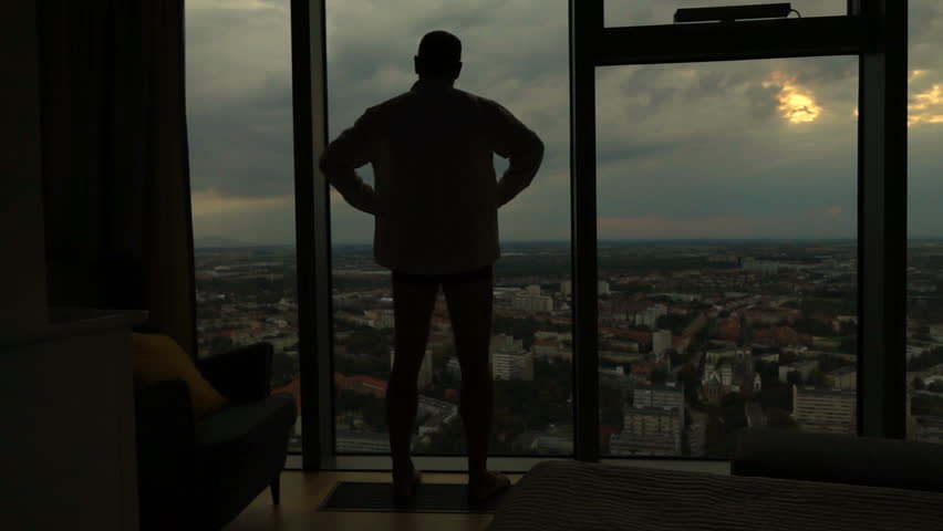 Silhouette of man admire sunset from window
