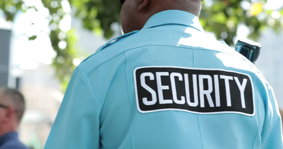 Security guard standing on guard overlooking territory and seeing if everything is safe. Security tag stamped on black man's uniform Royalty-Free Stock Footage #32040595