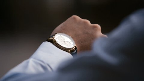 Young male business man is waiting for a meeting. Hand with a clock close up. Waits. Looks at the clock, time.