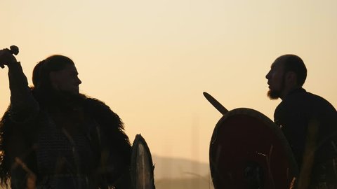 Silhouettes of warriors Viking are fighting with swords and shields. Contre-jour