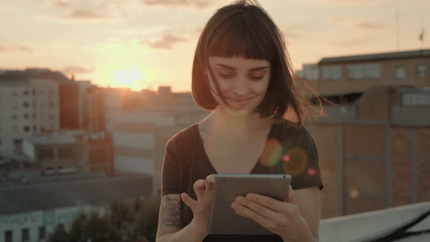 Attractive millennial young woman or happy pretty teenager stands in middle of busy buzzling city on summer sunset night. she uses mini tablet full of applications and technology Royalty-Free Stock Footage #32044756