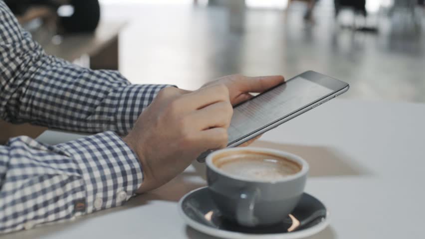 Close up on male office worker or young freelancer in casual business outfit during lunch break next to creative startup hub or in coworking space, types code or text on tablet device | Shutterstock HD Video #32044780