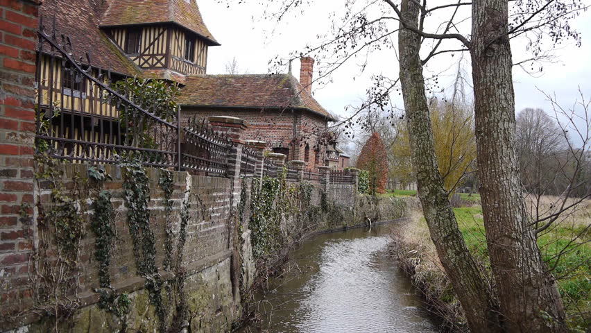 Old house in Beuvron en Auge France wih a small flowing river.