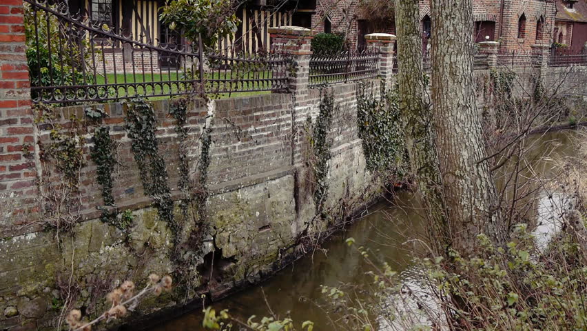 Old wall with a small flowing river in Beuvron en Auge France.