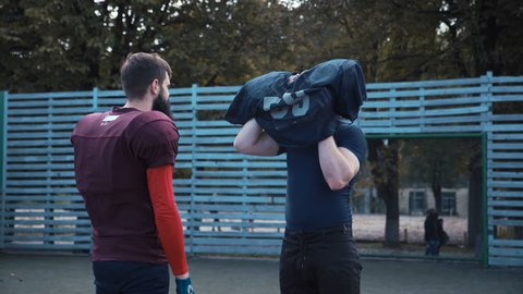 American football player helping his mate to put on jersey before game on field Stock Video