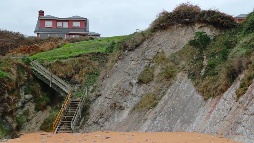 House in a hill with a wooden stairs to the beach.