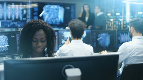 Female Computer Engineer Works on a Neural Network Artificial Intelligence Project with Her Multi-Ethnic Team of Specialist. Office Has Multiple Screens Showing 3D Visualisation.Shot on RED EPIC-W 8K