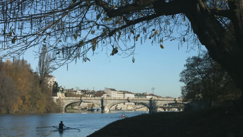 Turin in autumn along the Po river with rowers training and historical bridge in the backgorund. The city hosted the XX Winter Olympic Games in 2006