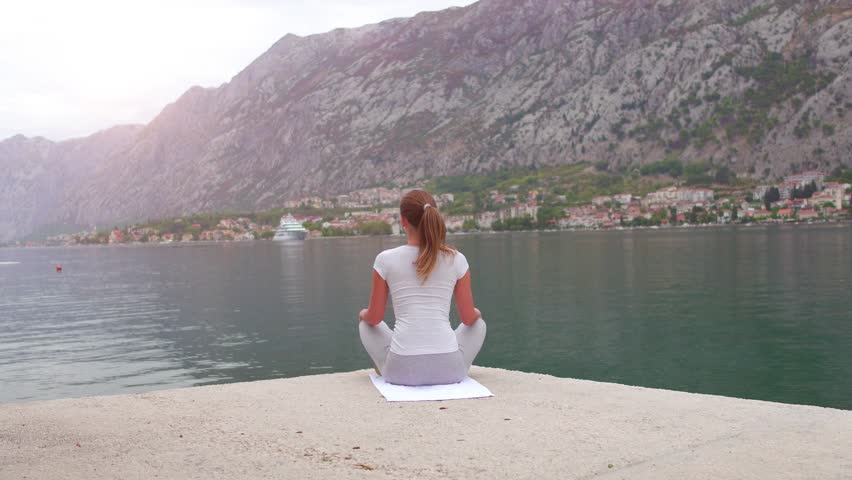 Young sporty woman doing youga at the mountins