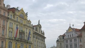 Pan of top of colourful buildings to Jas Hus Statue on Old Town Square in Prague, Czech Republic