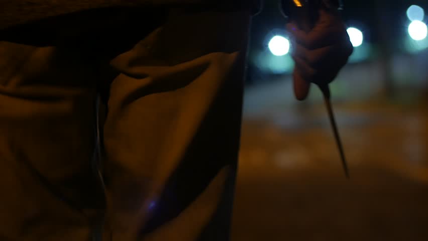 A MAN WALKS AT NIGHT HOLDING A BIG KNIFE, BLURRED BACKGROUND, WAIST AND HAND SEEN Royalty-Free Stock Footage #32070352