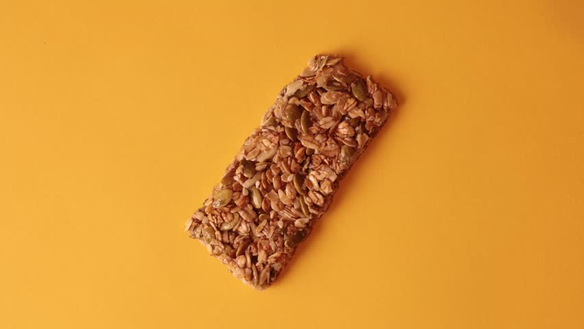 Granola bar bites stop motion on solid orange background with granola crumbs stopmotion Royalty-Free Stock Footage #32076262