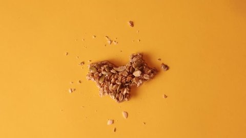 Granola bar bites stop motion on solid orange background with granola crumbs stopmotion