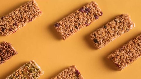 Different flavor granola stopmotion, bars moving along a solid orange background stop-motion from top-view