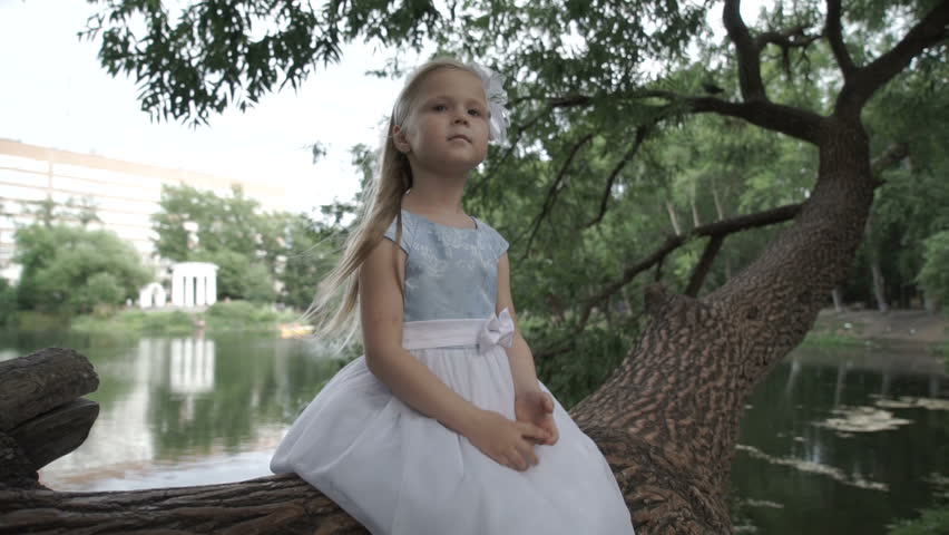 Little girl is sitting on a tree